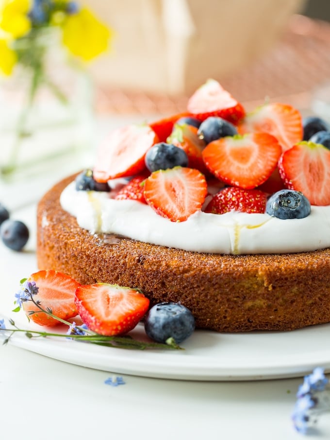 coconut flour cake with whipped cream and berries and drizzled with a bit of honey