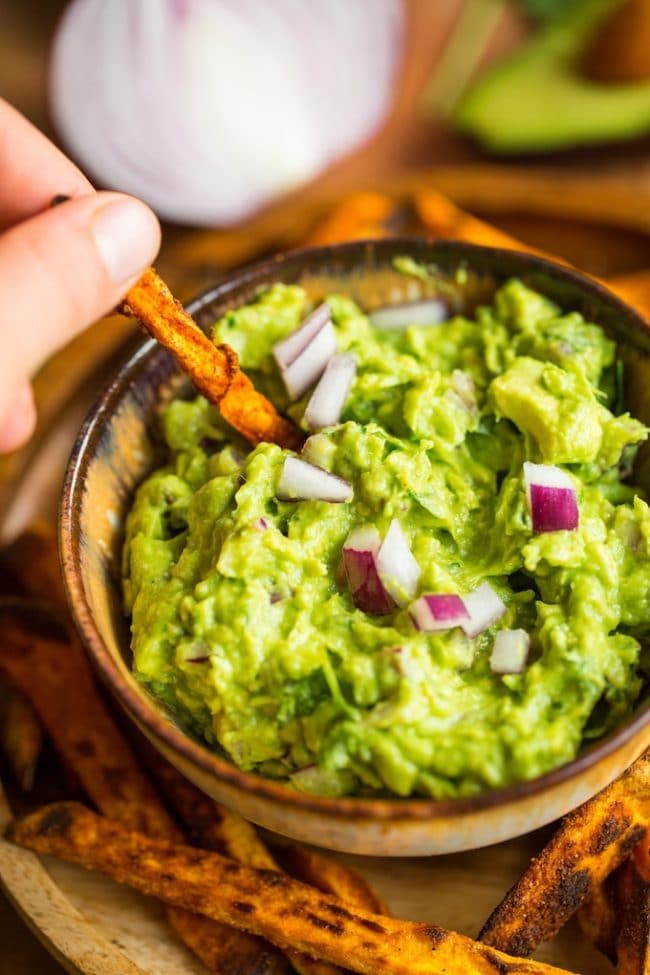 Sweet potato fry dipping into Homemade Guacamole Recipe