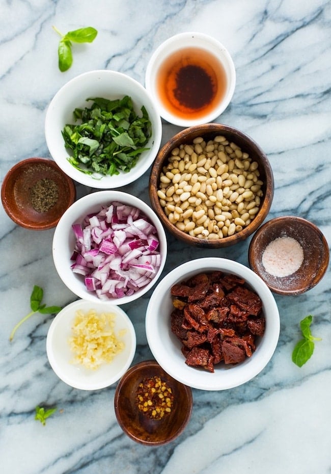 Sun Dried Tomato Cannellini Bean Salad ingredients separated into individual bowls: basil, tomatoes, onion, garlic, salt, pepper, and pine nuts