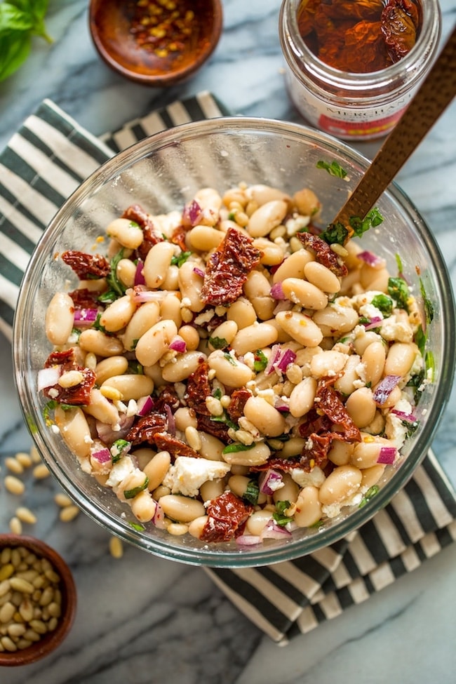 Sun Dried Tomato Cannellini Bean Salad in a salad bowl on a stripped napkin