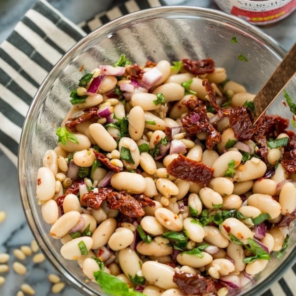 Sun Dried Tomato Cannellini Bean Salad in a salad bowl on a stripped napkin