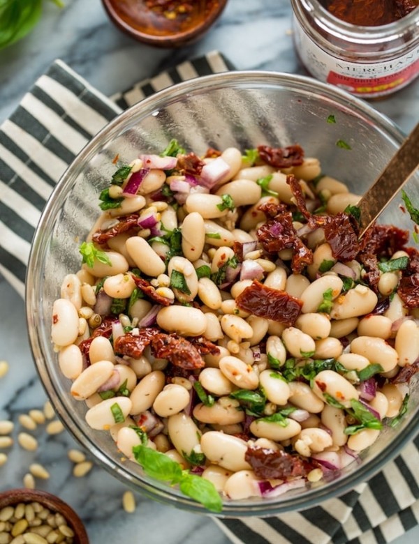 Sun Dried Tomato Cannellini Bean Salad in a salad bowl on a stripped napkin