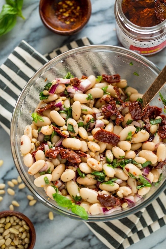 Sun Dried Tomato Cannellini Bean Salad in a salad bowl on a stripped napkin