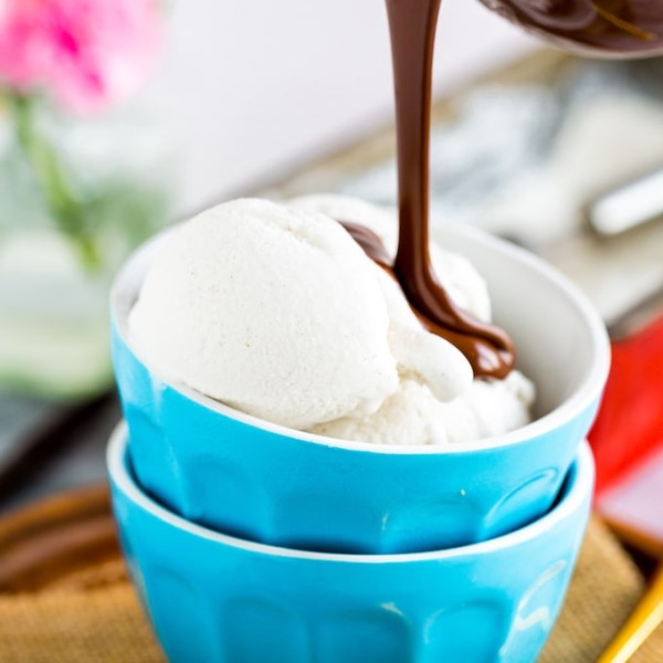 a small bowl of Coconut Vanilla Ice Cream with hot fudge pouring over the top