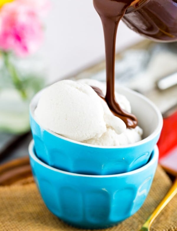 a small bowl of Coconut Vanilla Ice Cream with hot fudge pouring over the top