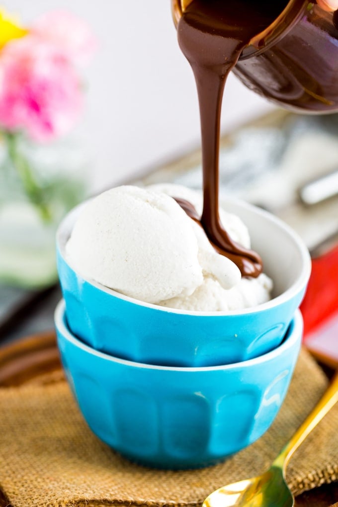 Dairy Free Hot Fudge pouring over a bowl of vanilla ice cream