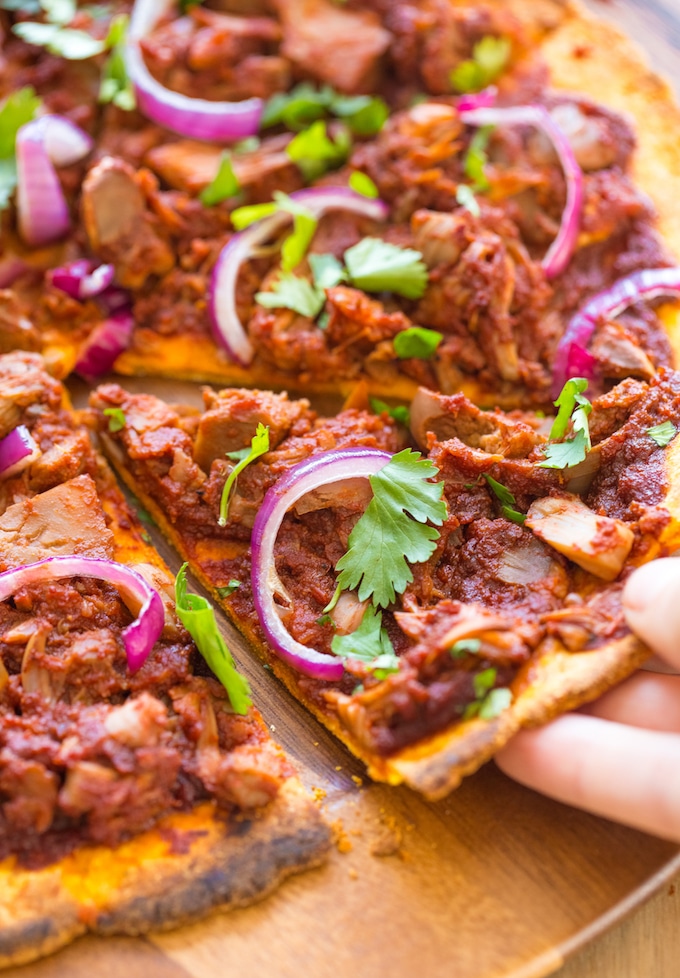 hand reaching for a slice of Jackfruit BBQ Pizza with a Sweet Potato Crust