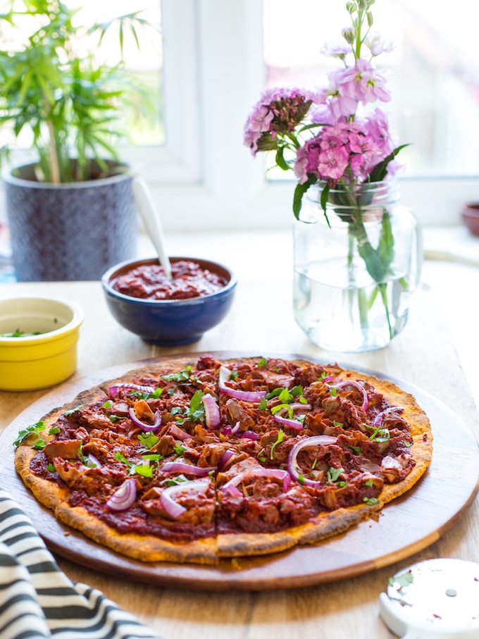 Jackfruit BBQ Pizza with a Sweet Potato Crust on a table in front of a window