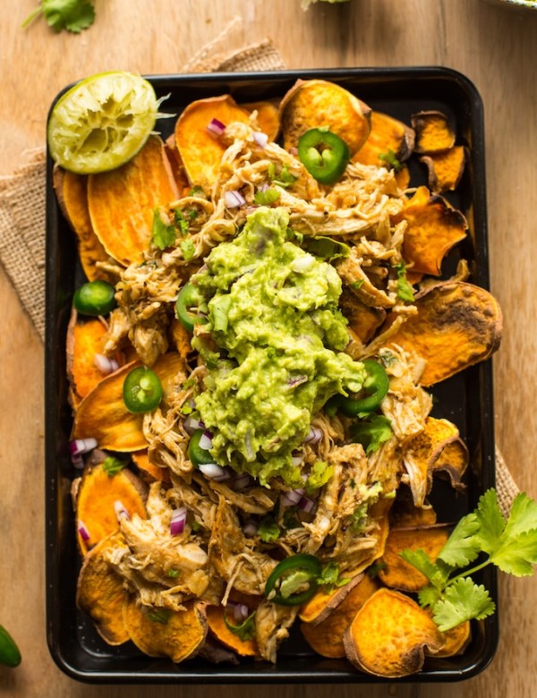 Sweet Potato Nachos on a baking sheet topped with chicken carnitas, guacamole and cilantro