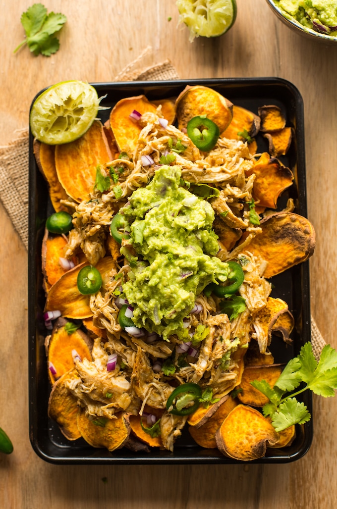Sweet Potato Nachos on a baking sheet topped with chicken carnitas, guacamole and cilantro