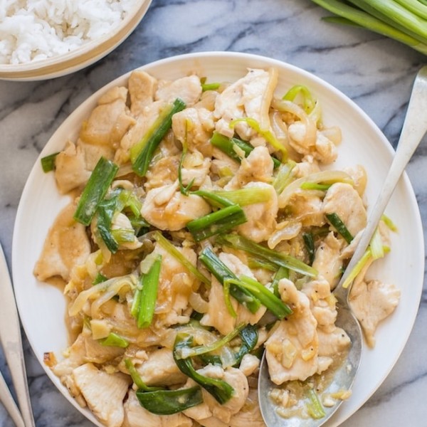 Garlic Ginger and Spring Onion Chicken on a serving plate with a spoon on a marble counter top