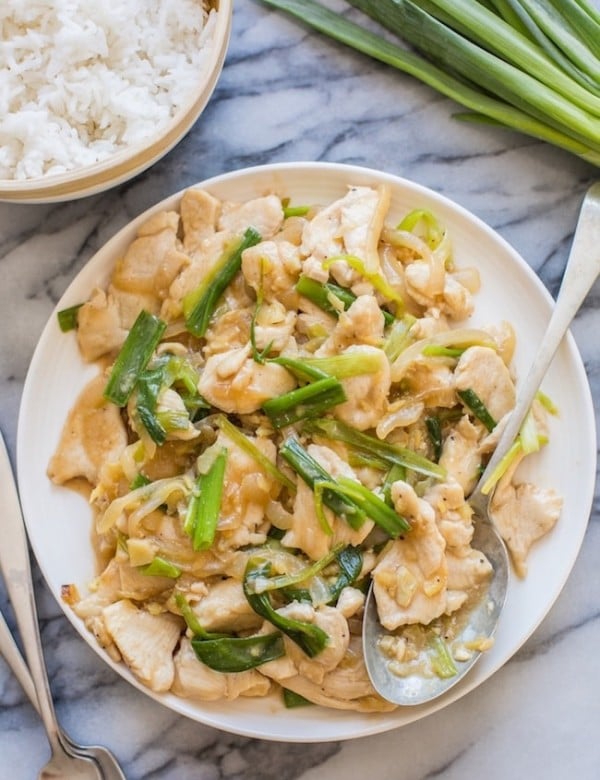 Garlic Ginger and Spring Onion Chicken on a serving plate with a spoon on a marble counter top