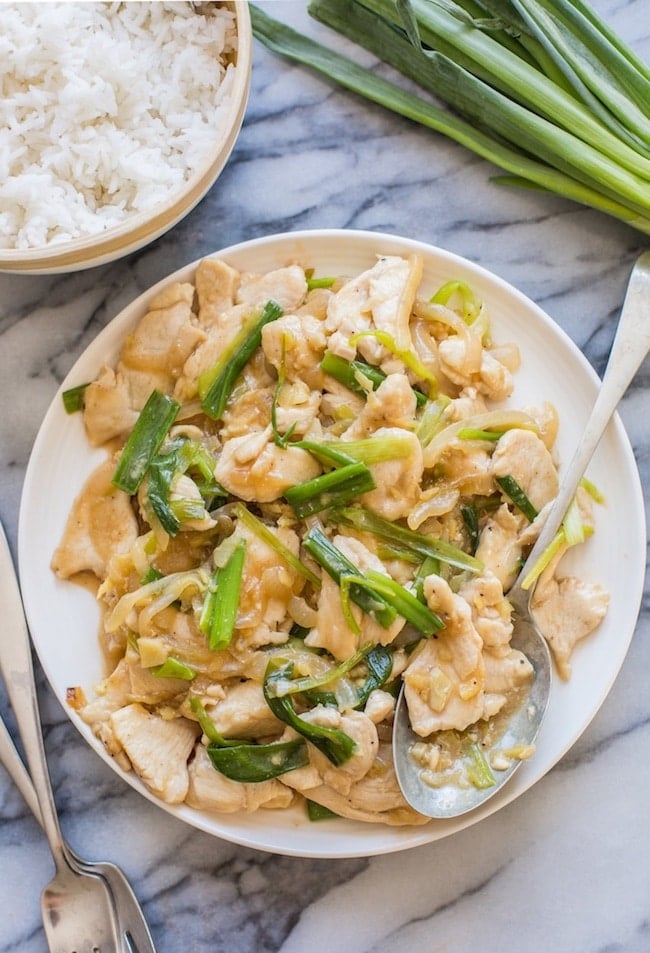 Chicken with Ginger and Spring Onion on a serving plate with spring onions on the side