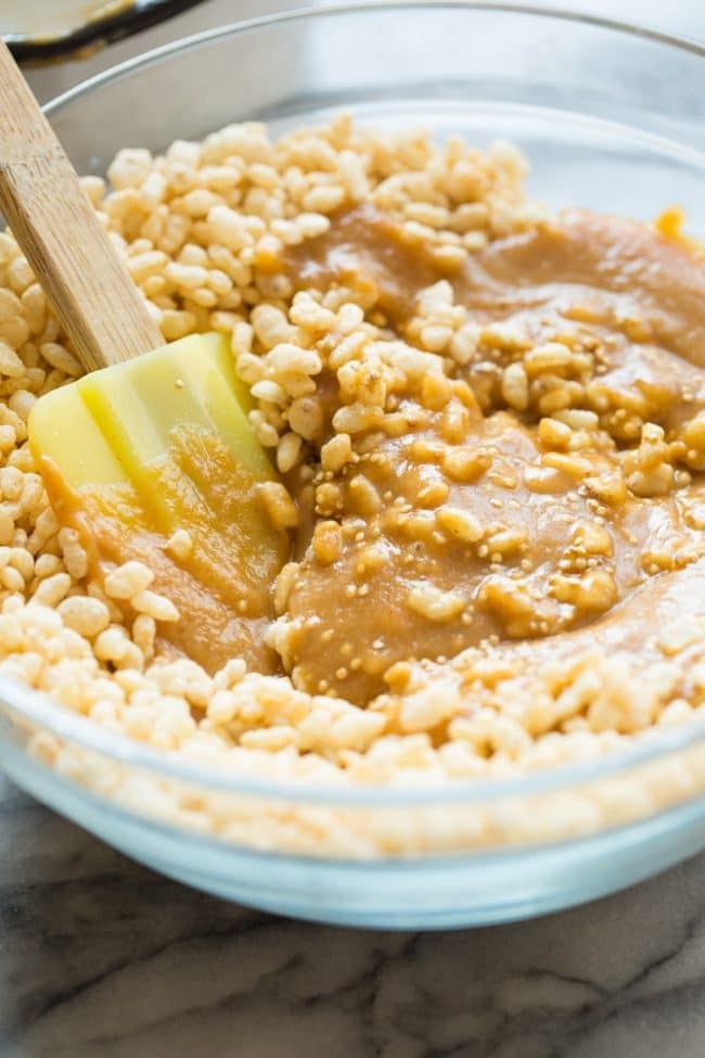 mixing together the rice crispy base of the Toasted Quinoa Peanut Butter Scotcharoos