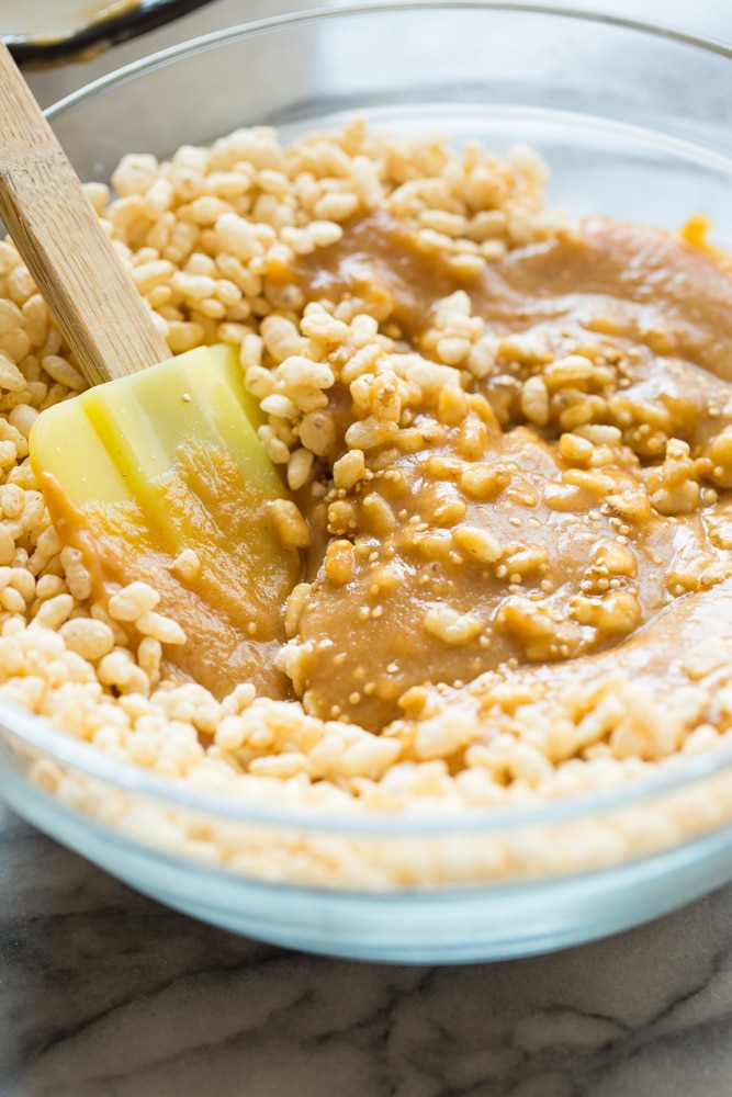 mixing together the rice crispy base of the Toasted Quinoa Peanut Butter Scotcharoos