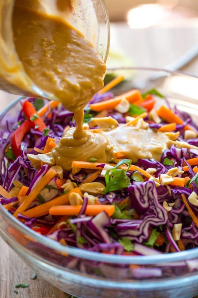 peanut dressing pouring onto Thai Peanut Coleslaw 