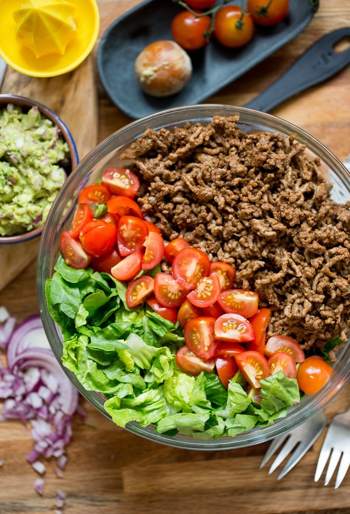 Whole30 Taco Salad: ground beef, chopped tomatoes and lettuce in a salad bowl with guacamole on the side