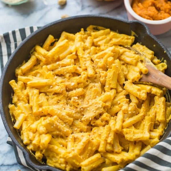 vegan pumpkin mac and cheese in a cast iron skillet on a stripped towel