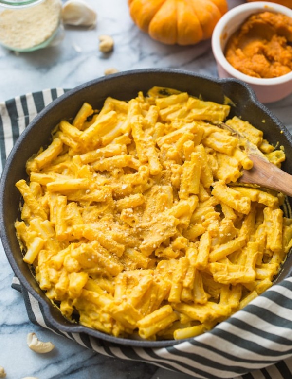vegan pumpkin mac and cheese in a cast iron skillet on a stripped towel