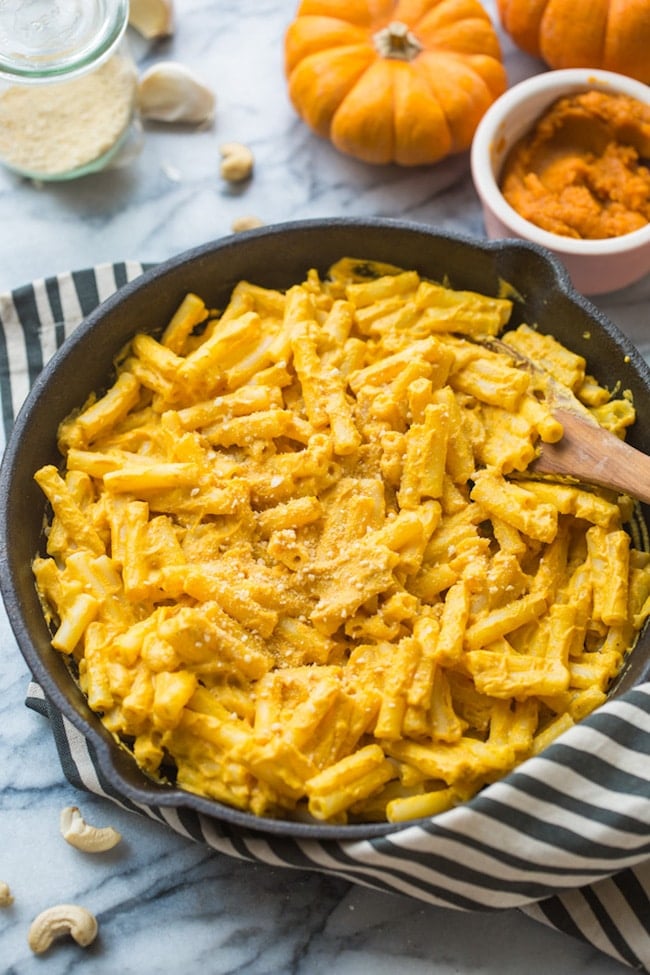 vegan pumpkin mac and cheese in a cast iron skillet on a stripped towel