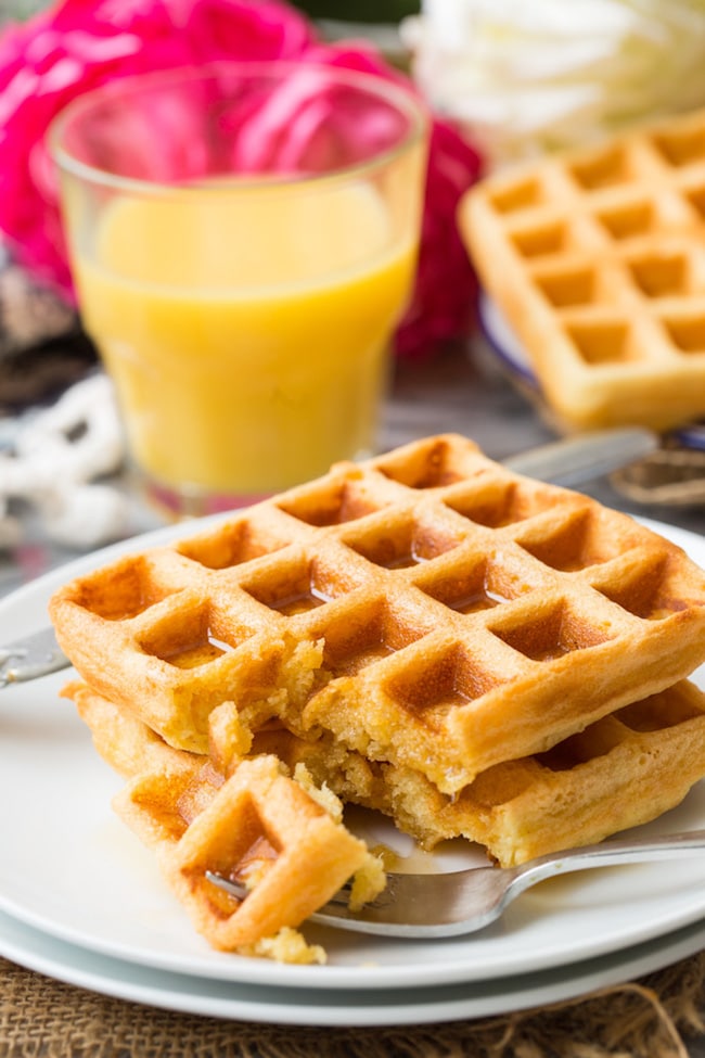 Gluten Free Waffles on a plate with maple syrup and a glass of orange juice