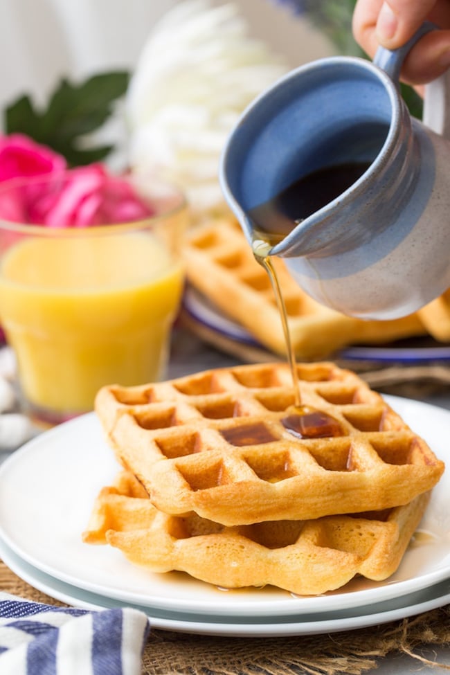 Gluten Free Waffles on a plate with maple syrup pouring over the top