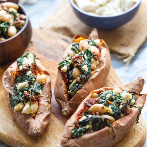 Spinach and Feta Stuffed Sweet Potatoes on a wooden cutting board with feta