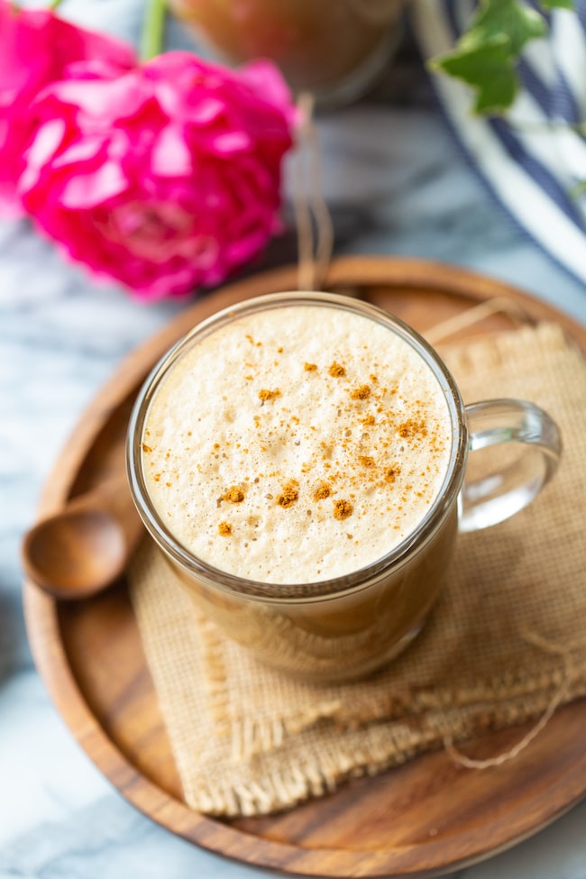 cashew butter latte on a wooden plate with a spoon sprinkled with cinnamon