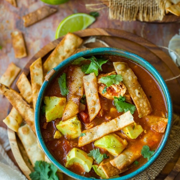 instant pot chicken tortilla soup topped with avocado and cilantro in a green bowl