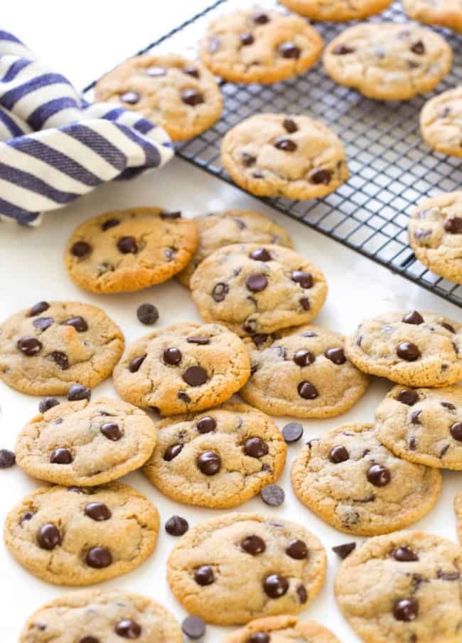 Almond Flour Chocolate Chip Cookies cookies in a pile with a wire cooling rack and tea towel in the back