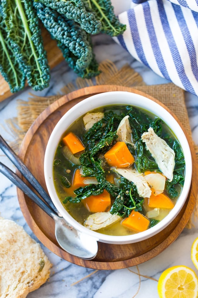 Sweet Potato Kale & Chicken Instant Pot Soup in a bowl on a wooden plate next to kale 