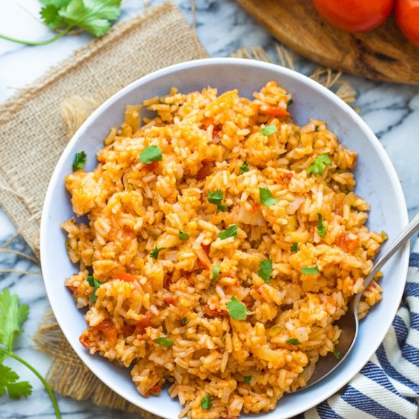 Mexican Rice in a bowl surrounded by tomatoes and cilantro