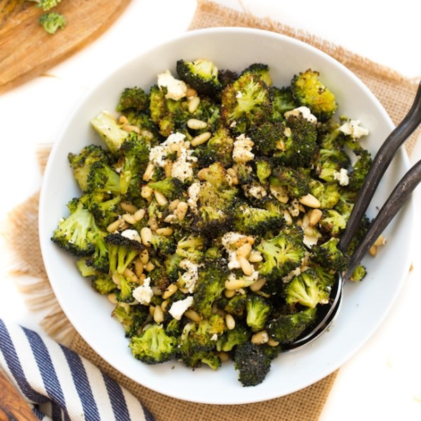 Roasted Broccoli Salad with Feta & Pinenuts in a serving bowl with serving spoons on the side