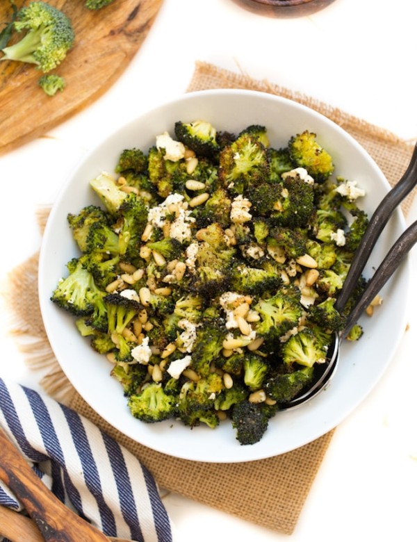 Roasted Broccoli Salad with Feta & Pinenuts in a serving bowl with serving spoons on the side