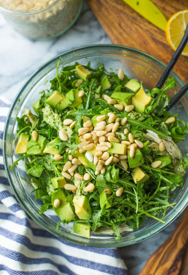 chicken pesto salad in a glass bowl topped with pine nuts 