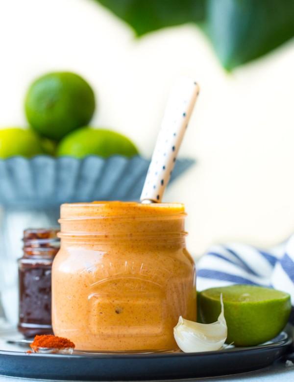 jar of chipotle mayo on a plate with garlic, lime and spices