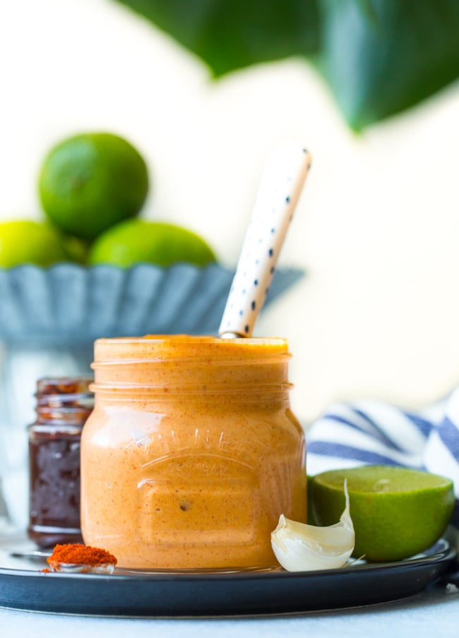 jar of chipotle mayo on a plate with garlic, lime and spices