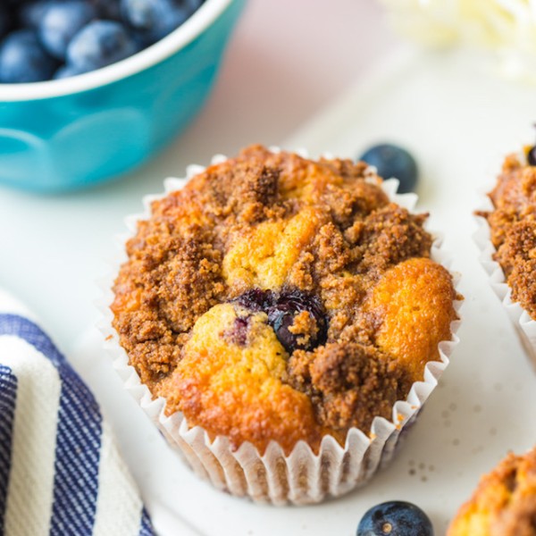 one Paleo Blueberry Muffin up close on a serving platter with a little bowl of blueberries behind