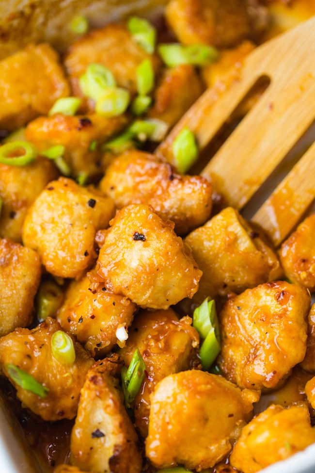 paleo fire cracker chicken topped with chopped spring onions stirred by a wooden spoon