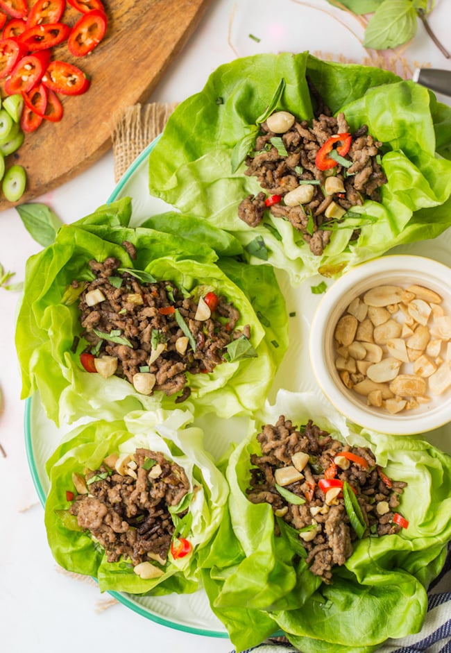 Spicy Beef Lettuce Wraps on a white platter topped with chopped peanuts 