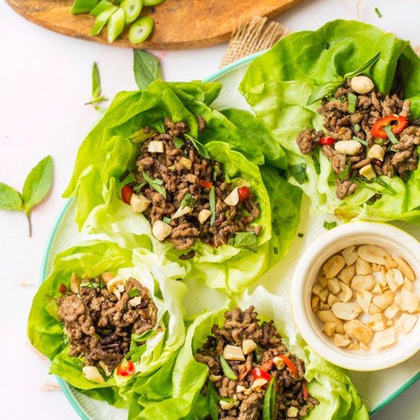 spicy beef lettuce wraps on a white serving platter topped with peanuts