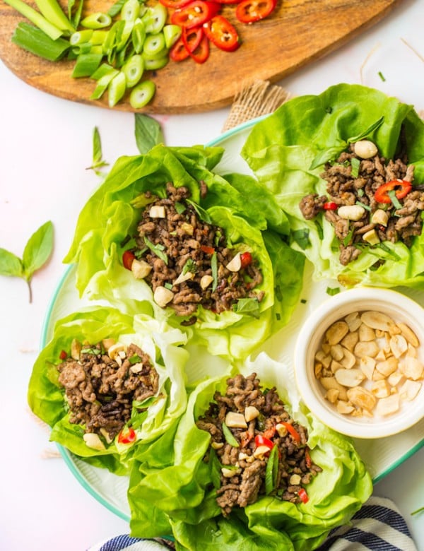 spicy beef lettuce wraps on a white serving platter topped with peanuts