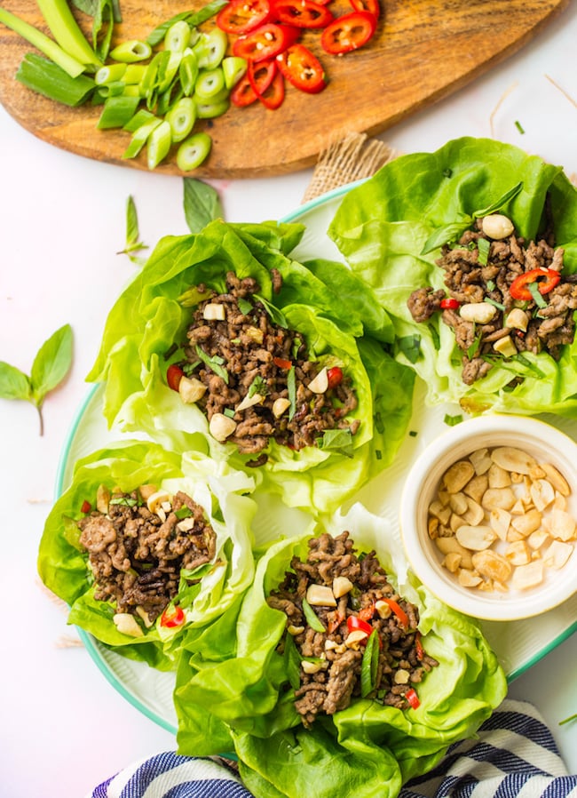 spicy beef lettuce wraps on a white serving platter topped with peanuts