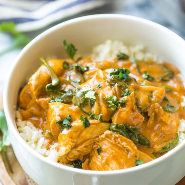 Tomato Coconut Curry Chicken in a white bowl topped with cilantro