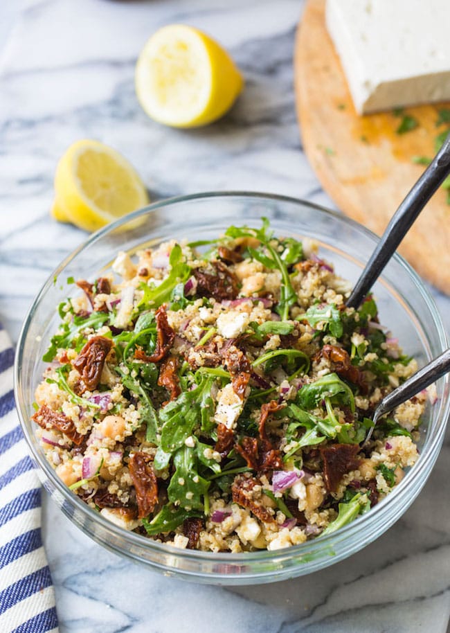 a salad bowl full of Chickpea Mediterranean Salad with Quinoa with feta and lemon on the side