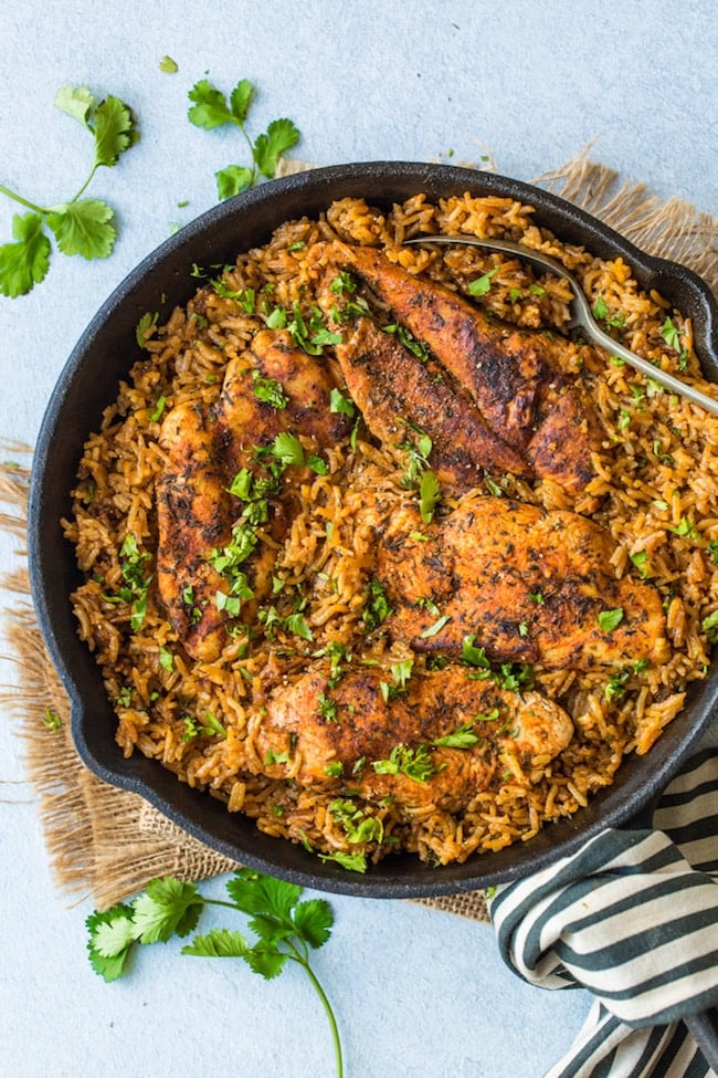 One Pot Chicken and Rice topped with chopped cilantro in a cast iron skillet