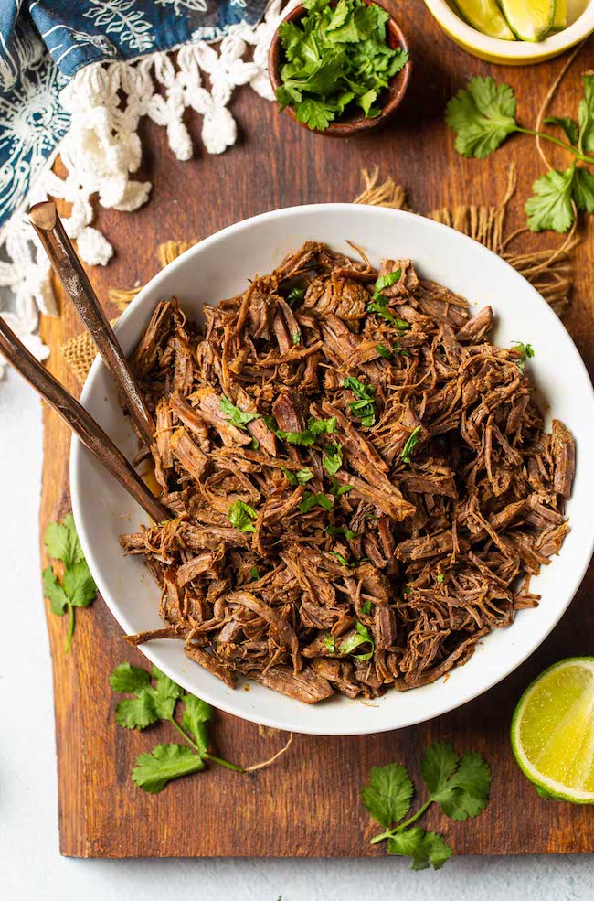 Beef Instant Pot Carnitas in a white bowl topped with cilantro 