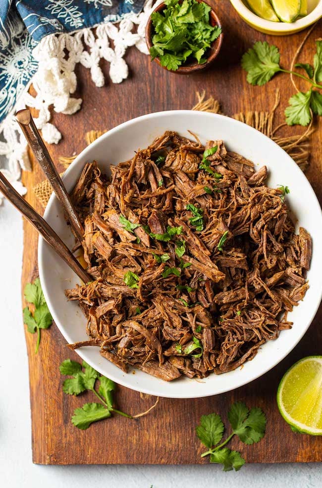 Beef Instant Pot Carnitas in a white bowl topped with cilantro