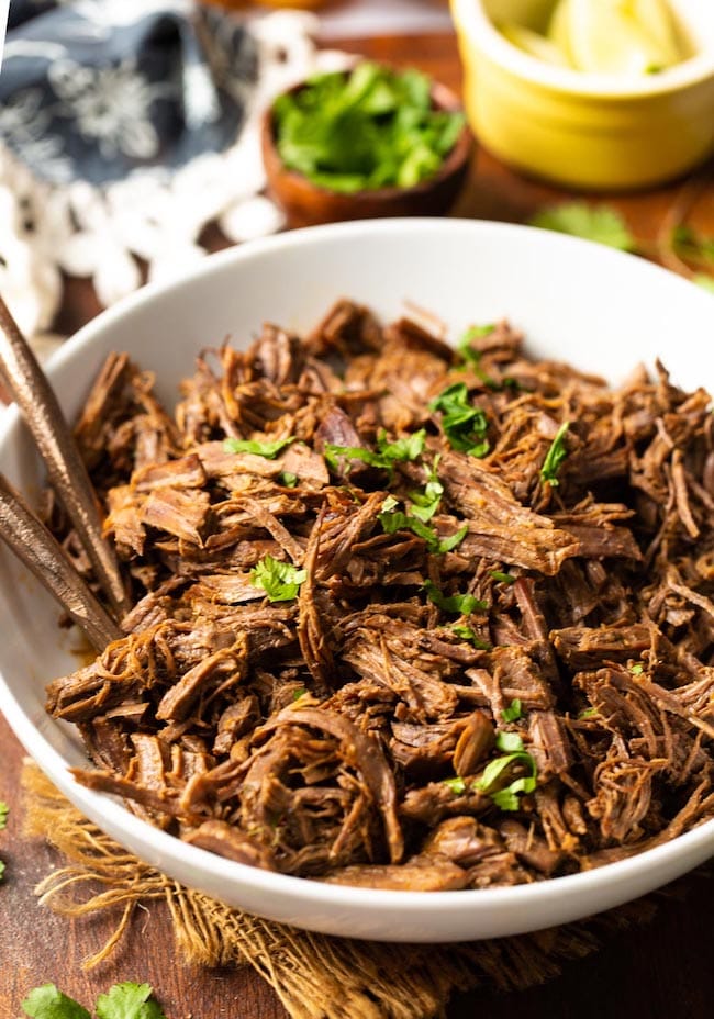 Beef Instant Pot Carnitas in a white bowl topped with cilantro 