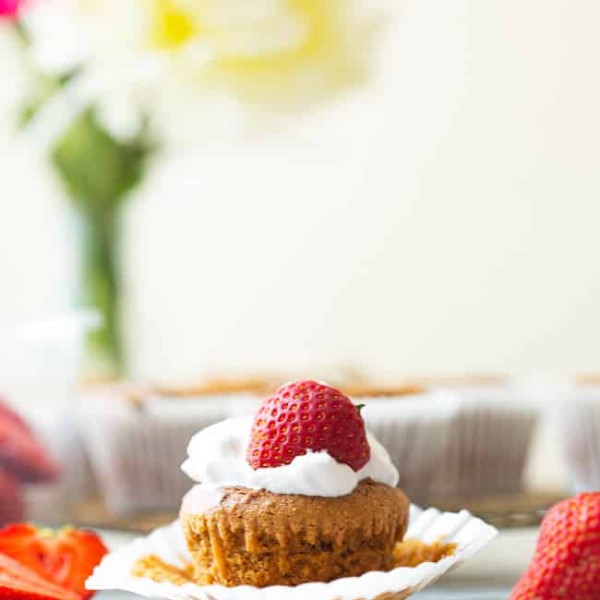 Paleo-Vegan-Cupcakes surrounded by fresh strawberries - one cupcake topped with whipped cream and a strawberry with the paper liner pulled back